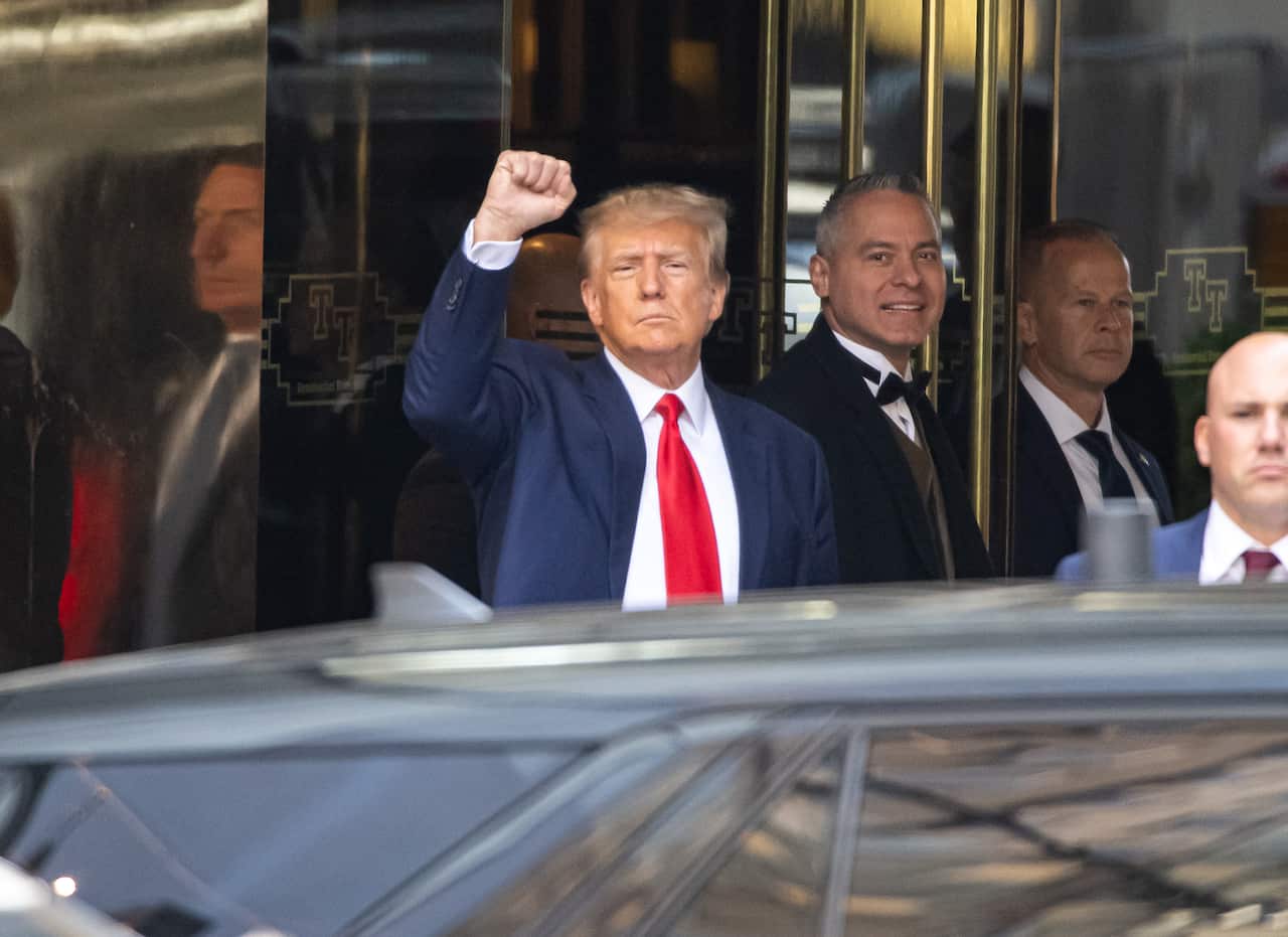 Former US President Donald Trump holds his fist in the air outside Trump Tower.
