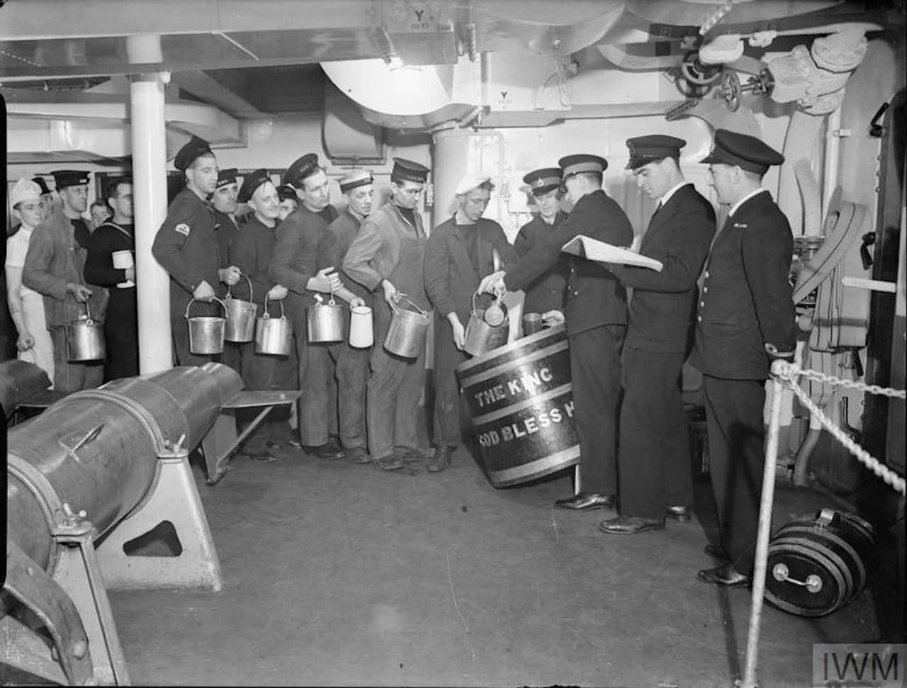 Beer and meals handed down to navy sailors who are standing in a line.
