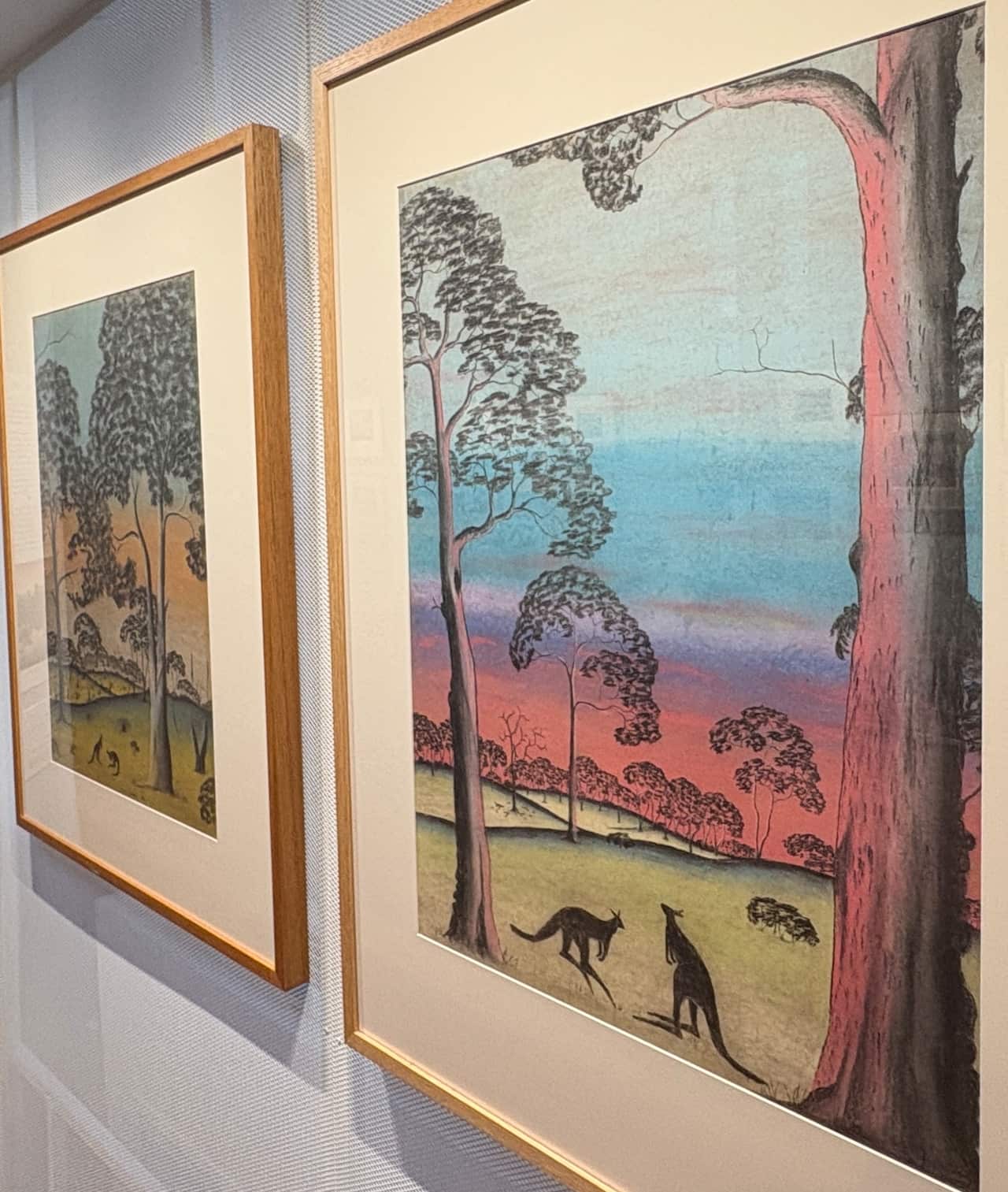 Two framed artworks depicting Australian landscapes hang on a wall.