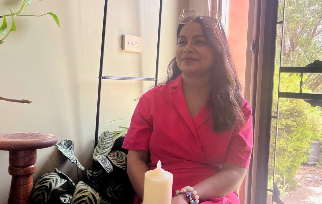 A woman sits on a chair and smiles.