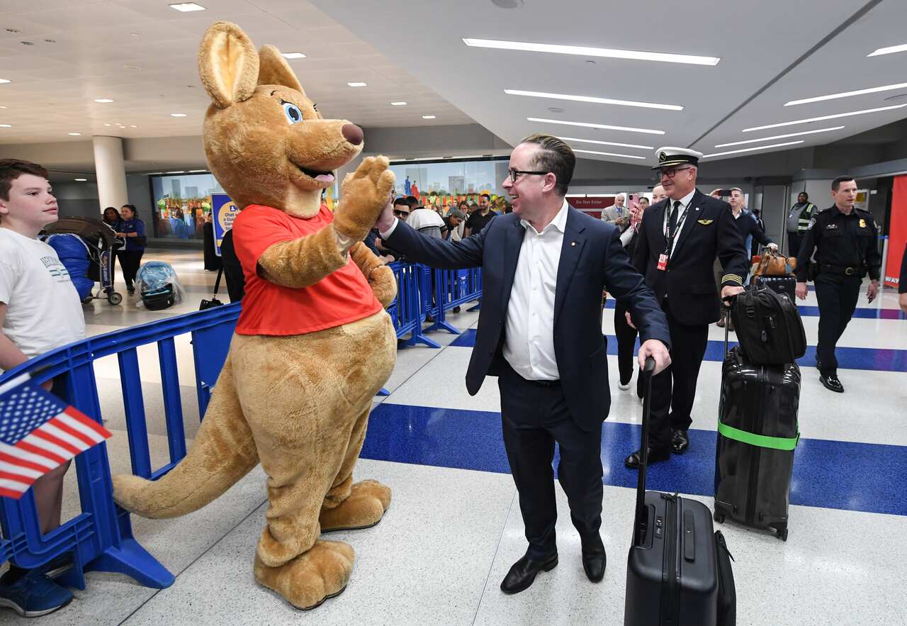 Alan Joyce next to a person wearing a kangaroo suit inside an airport.