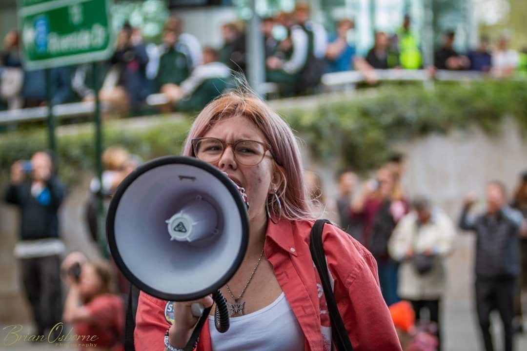 A young woman attending a protest, speaking into a megaphone. 