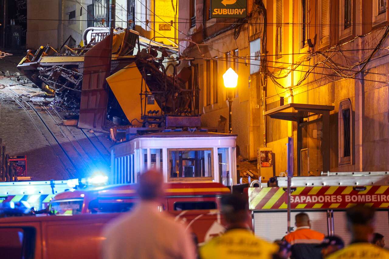 People looking up a road at a railway vehicle that has crashed. 