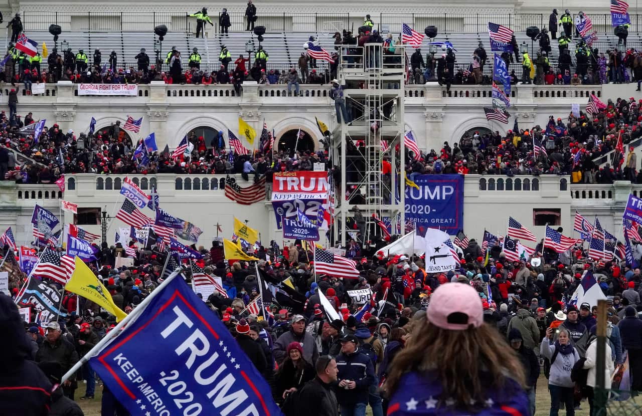 Lots of people carrying American flags in front of a white building.