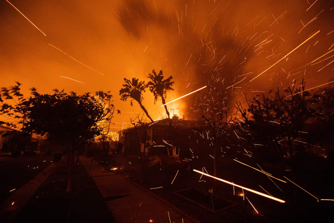 Flames and embers shoot from a burning home.