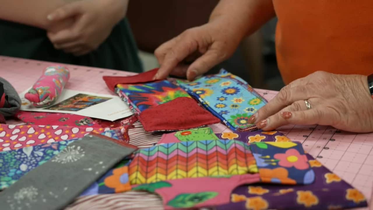 A number of pads and liners made from brightly patterned fabrics are spread out on a table.