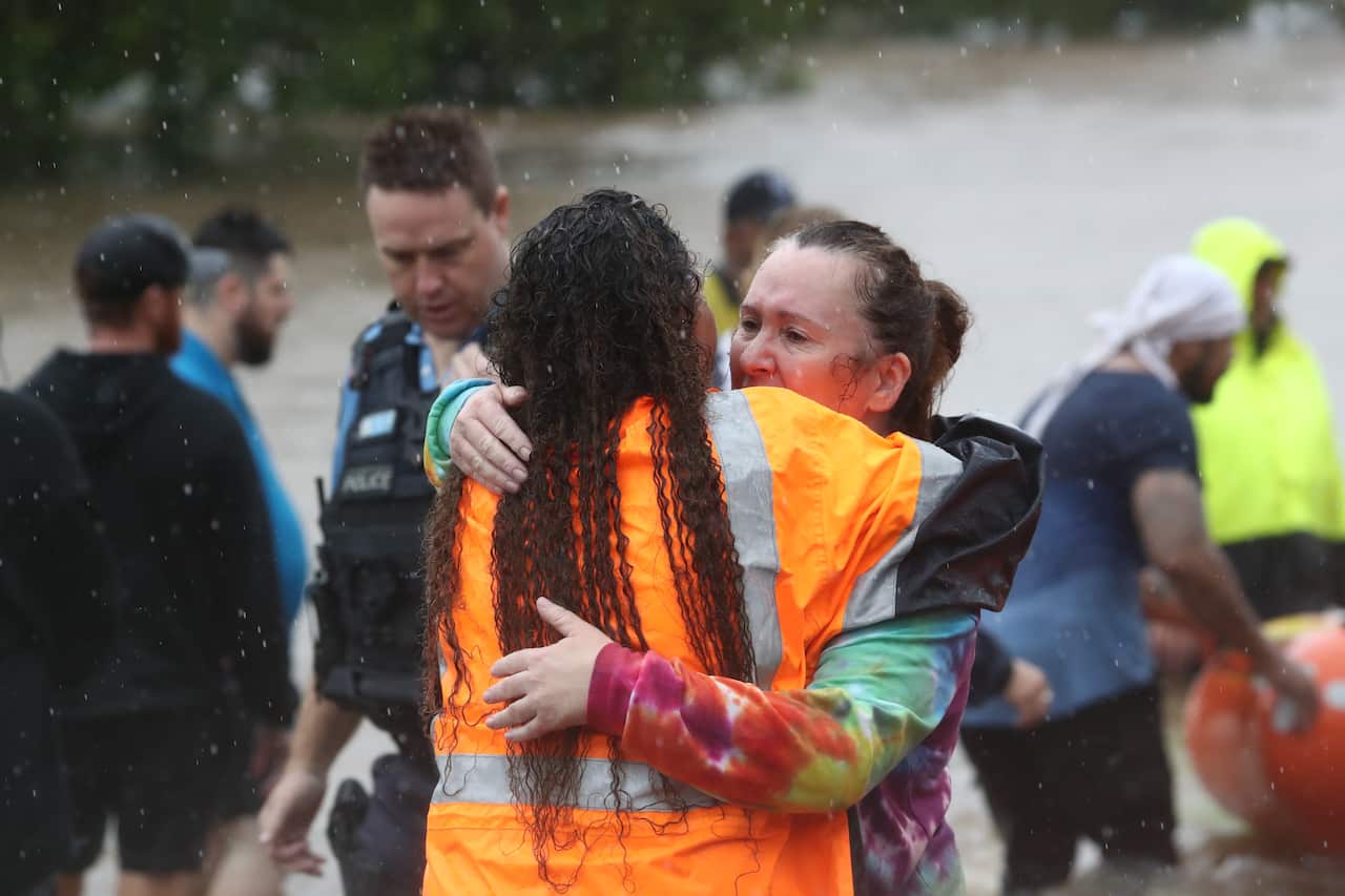 A rescue worker comforts a woman as floodwaters rise in Lismore, northeastern NSW.