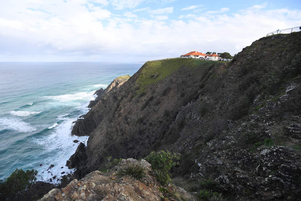 A cliff next to the ocean with a small structure on top.
