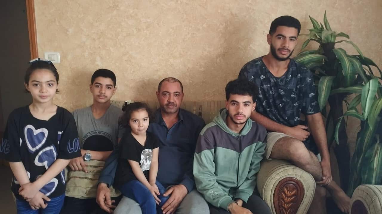 Six members of a family pose for a photo while seated on a couch.