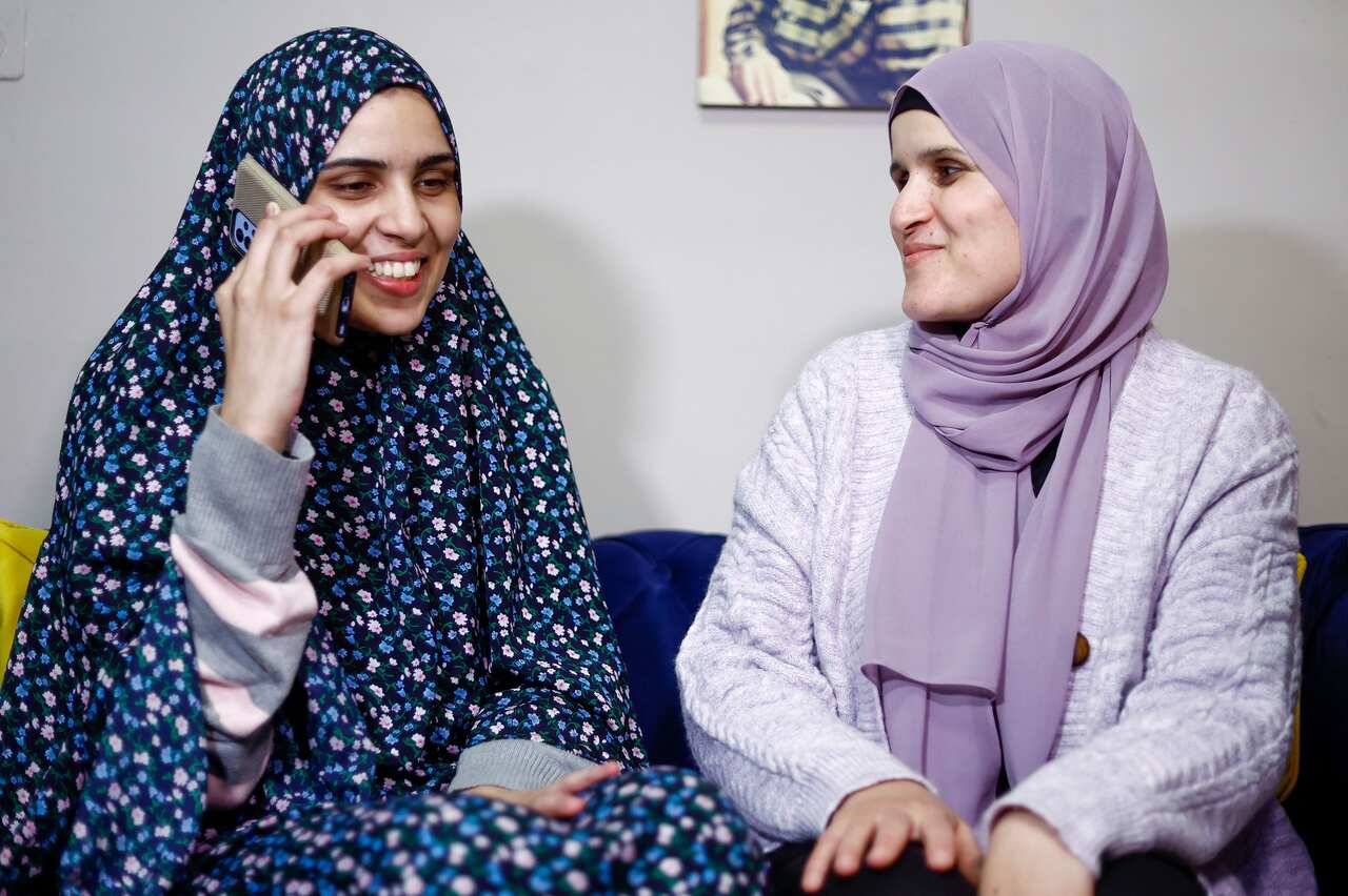 A woman speaks on the phone while another looks at her.