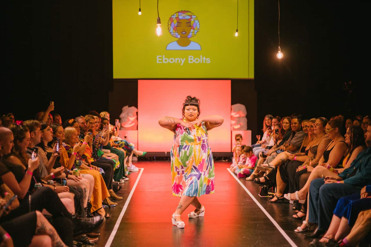 A woman in a colourful dress walking downa runway