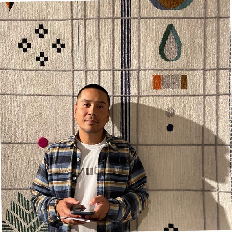 A man stands holding his phone.