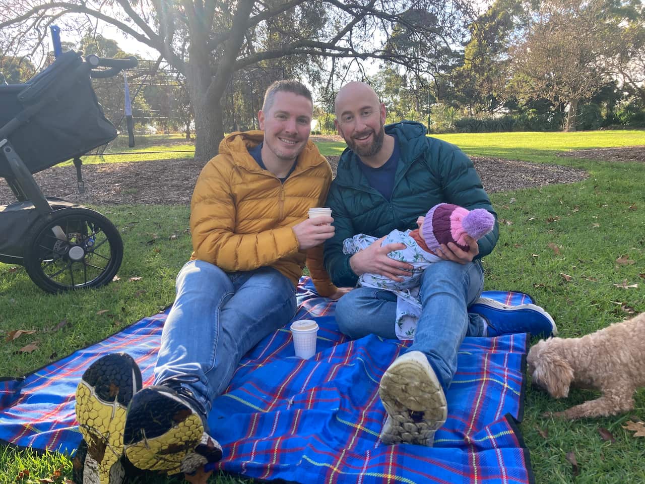 A man holding a baby sits next to another man