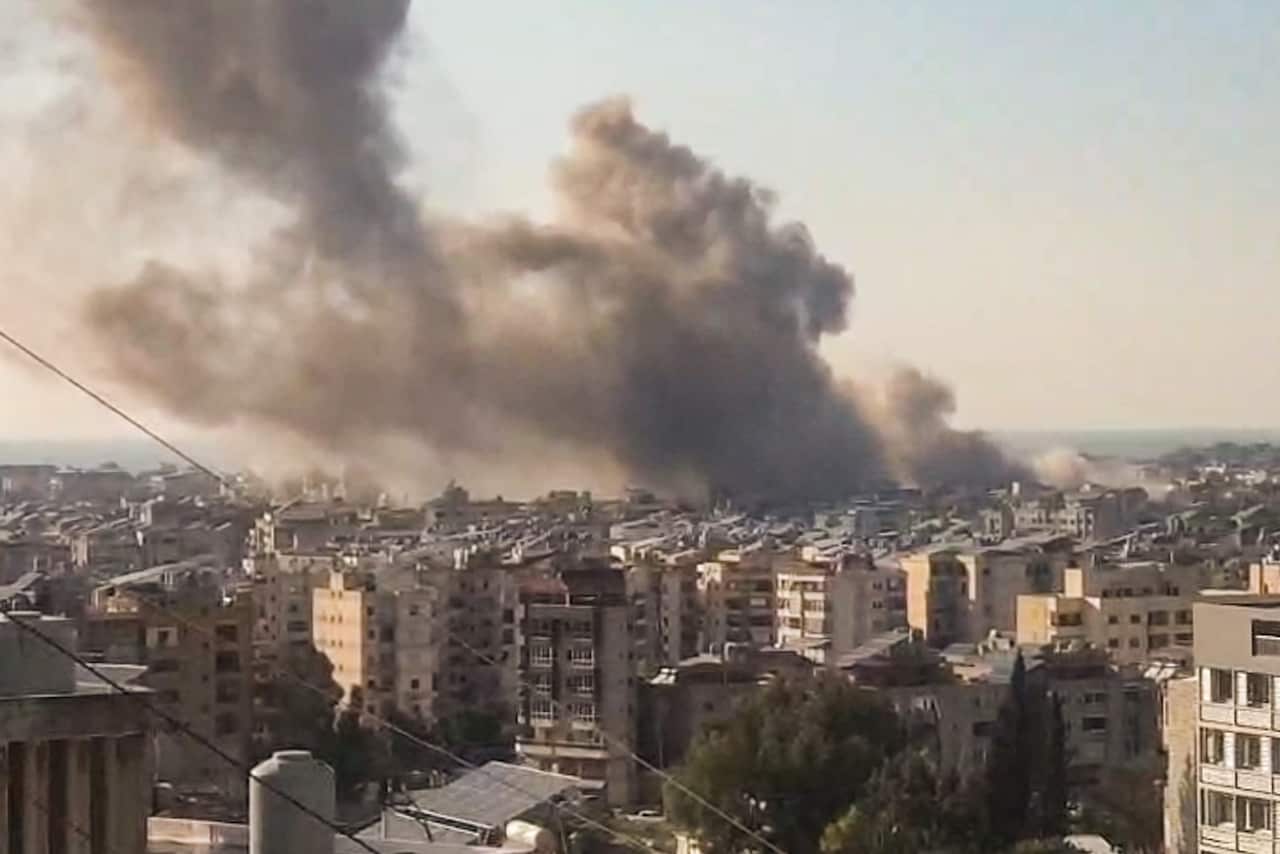 A cloud of smoke rising from above buildings.