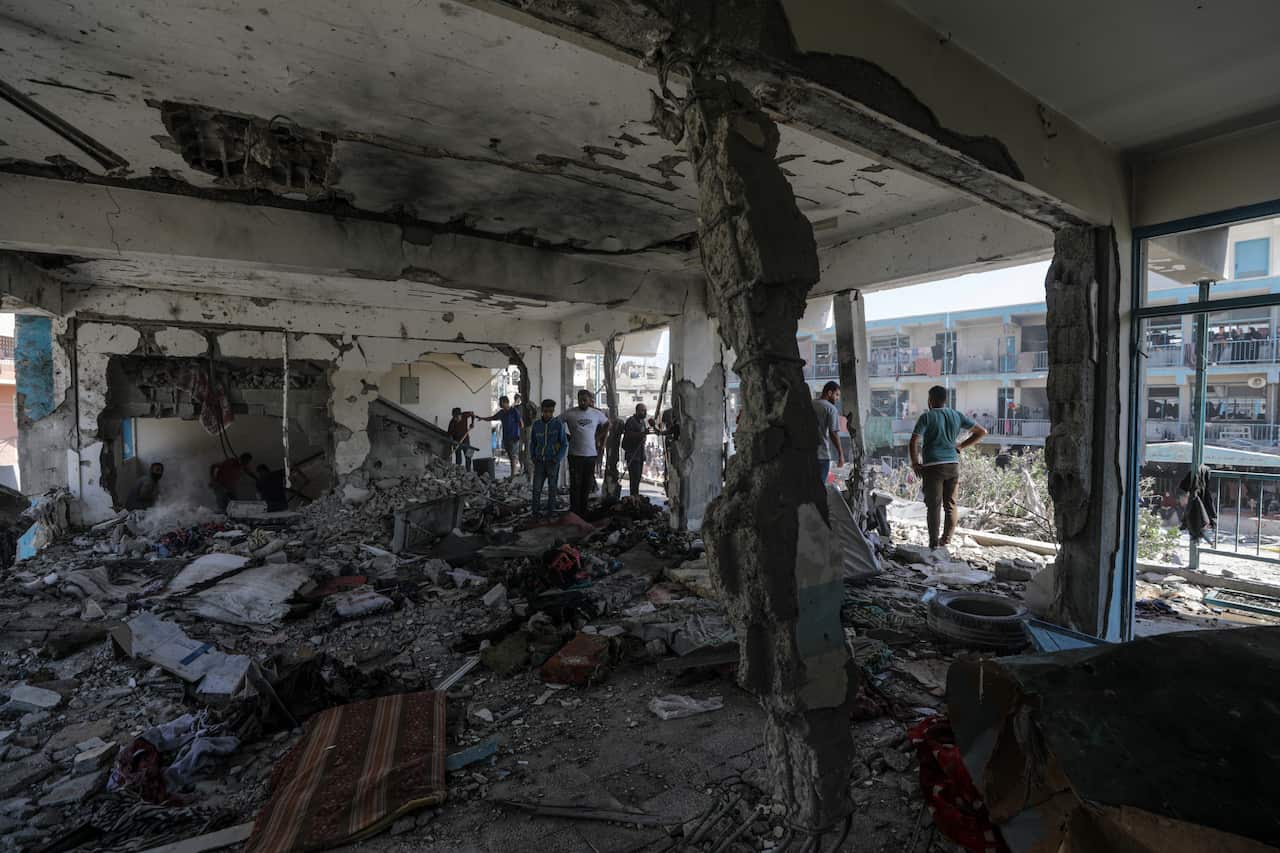 People stand amongst the rubble of a building that has been damaged.