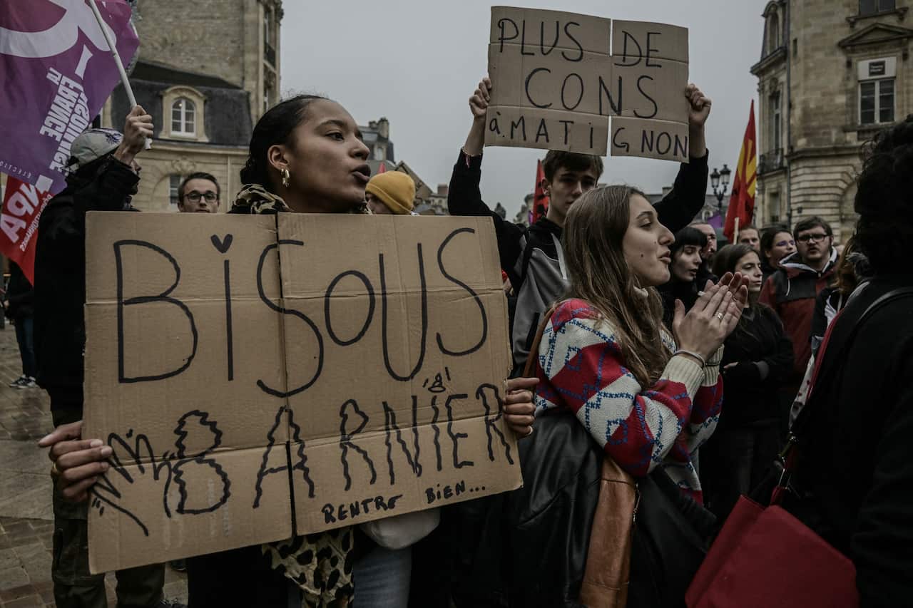 Protesters shout while holding carboard signs.