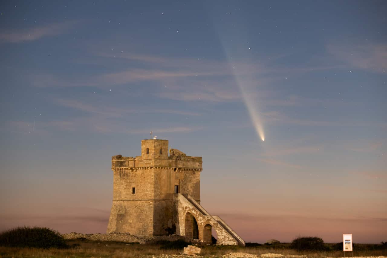 A comet descends from the top of the image, with a fortress-like structure in the lower left corner.