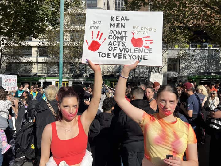 Two women hold up a sign at a protest