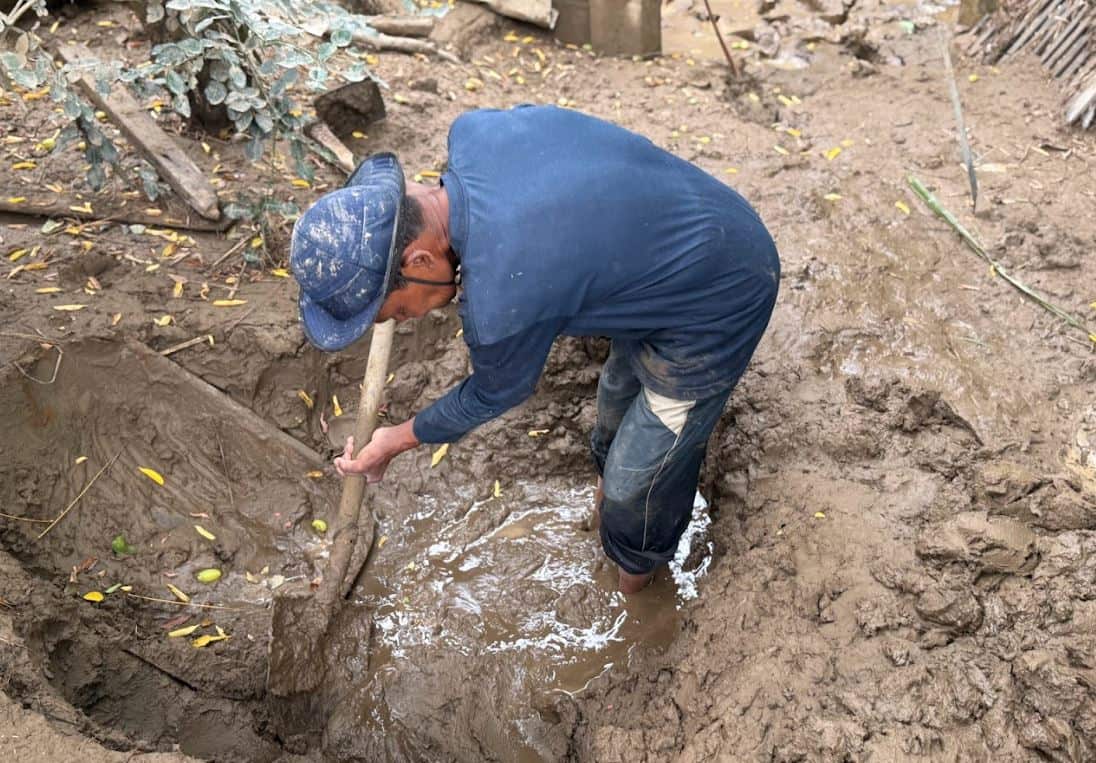 A man in blue shovels mud