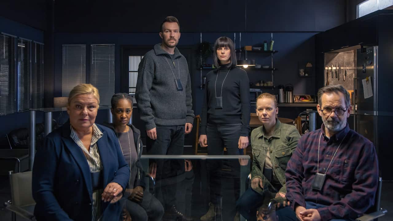 6 detectives, 2 standing 4 sitting sit in a room