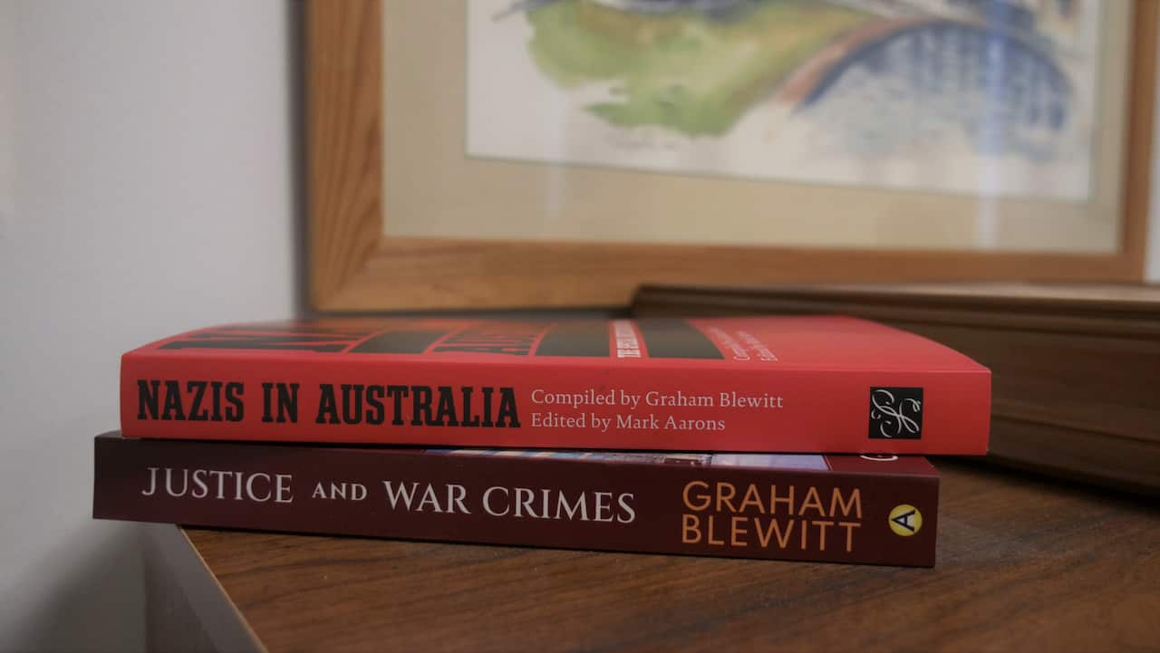 Two softcover books stacked on a wooden surface. The top book is bright red and titled Nazis in Australia. The bottom book is a darker burgundy colour, titled Justice and War Crimes.