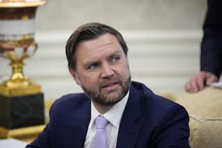 Vice President JD Vance in a blue suit and purple tie sitting on a golden couch looking a little concerned