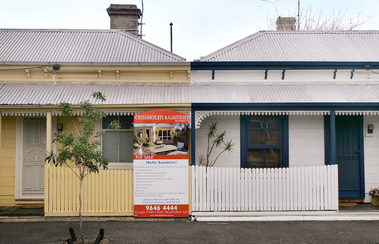 A for sale sign between two small houses 