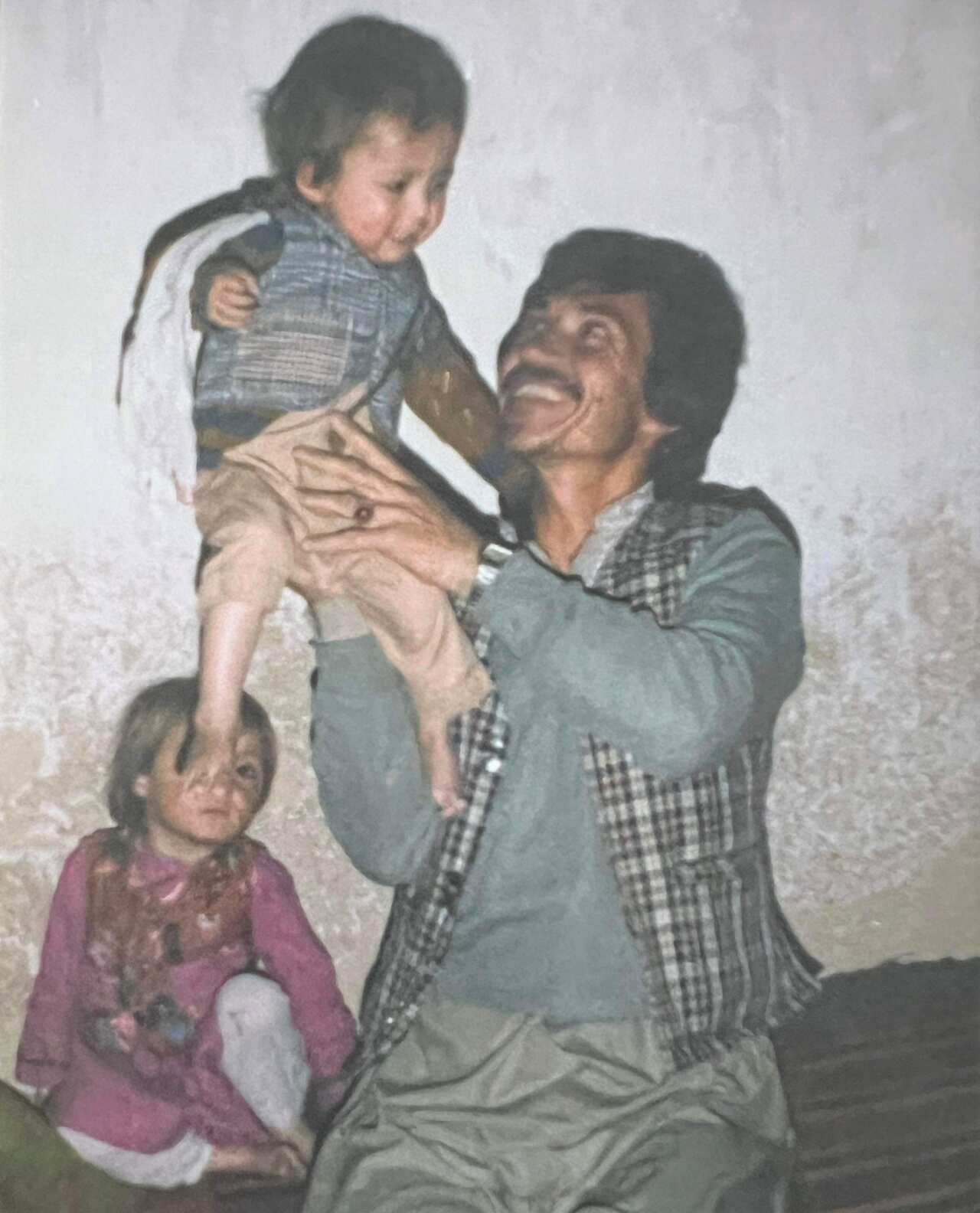 Hedayat sitting up on his uncle's shoulder as a toddler in Afghanistan.