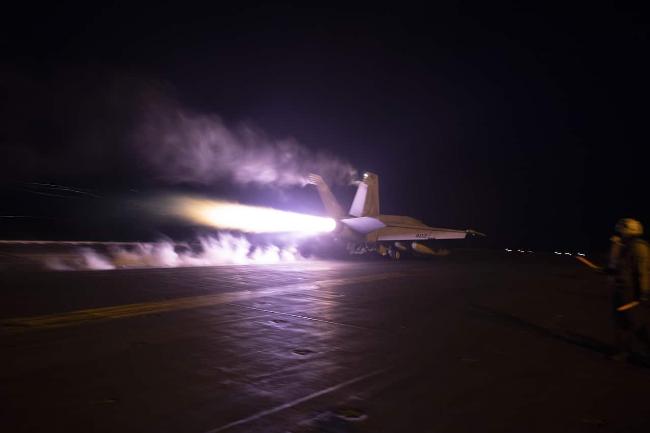A fighter plane on an aircraft carrier at night