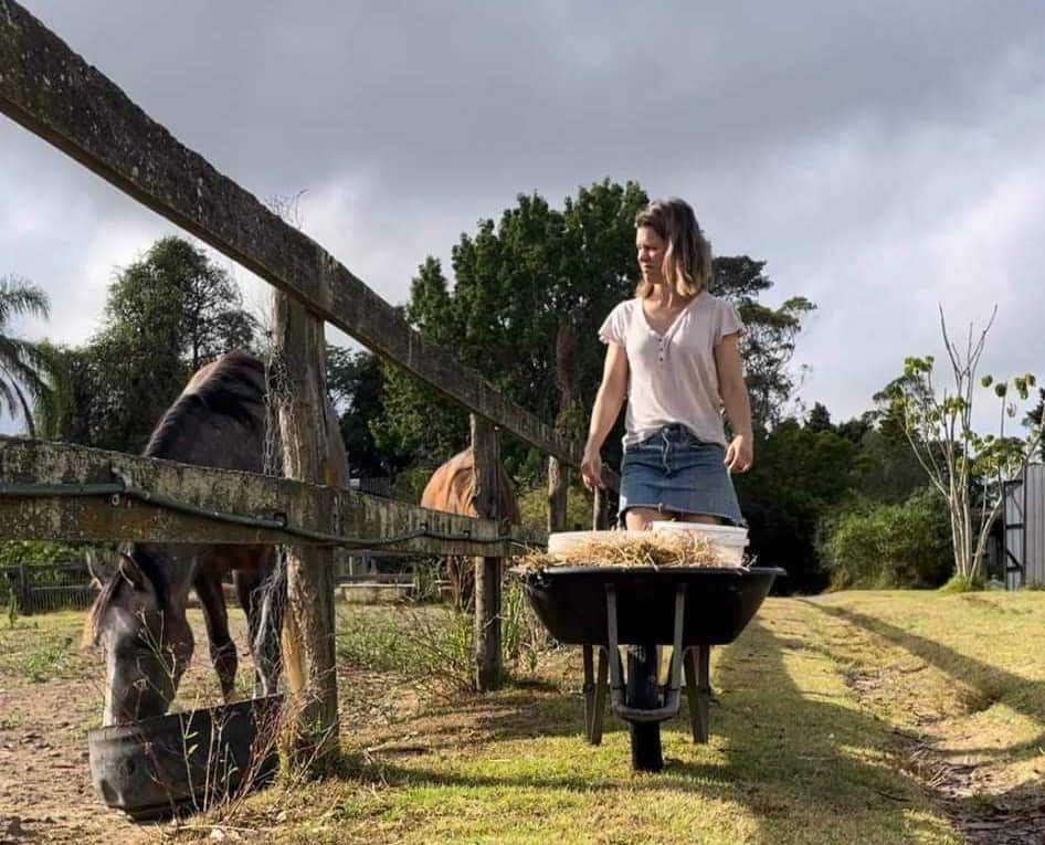 A woman pushes a wheelbarrow on a farm in NSW. 