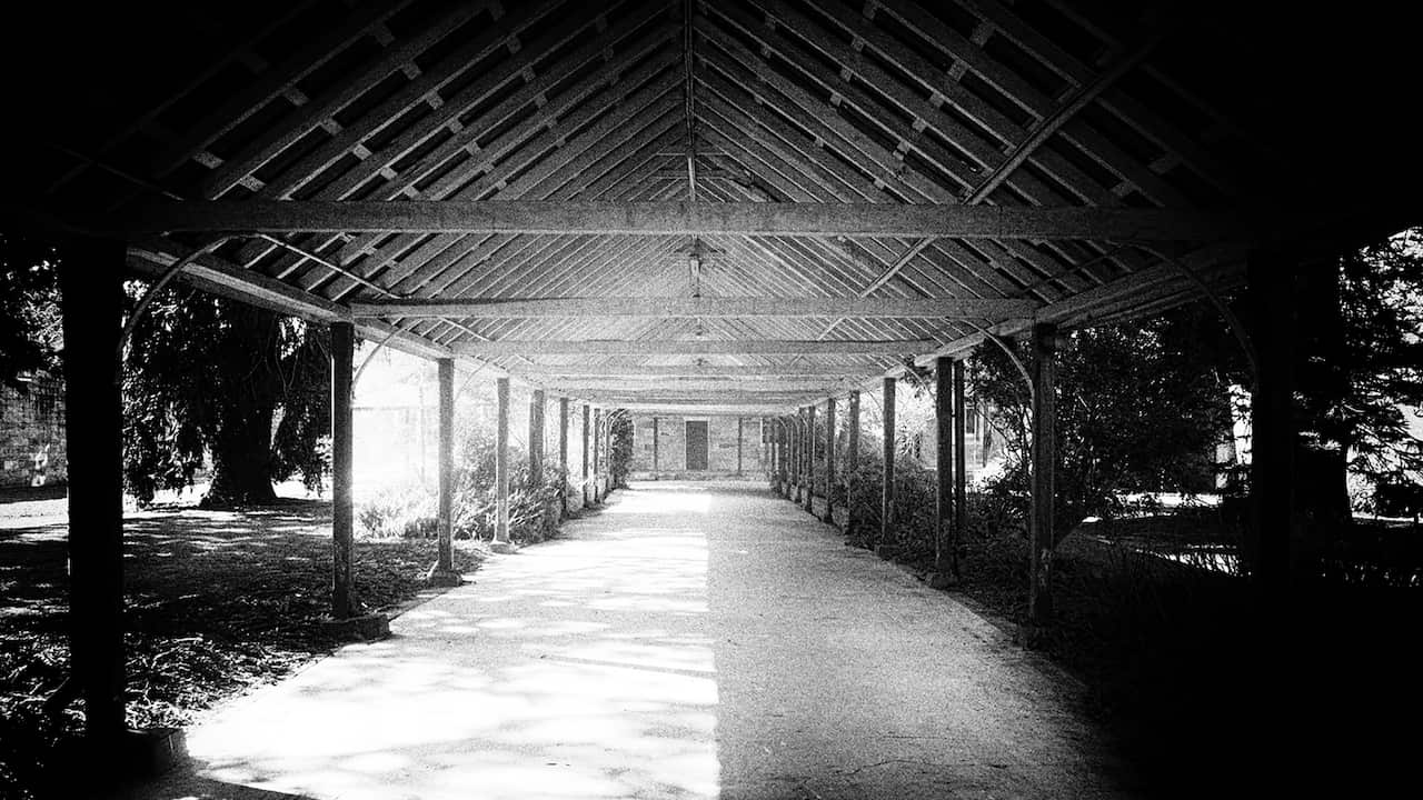a black and white image of a pergola and a brick building