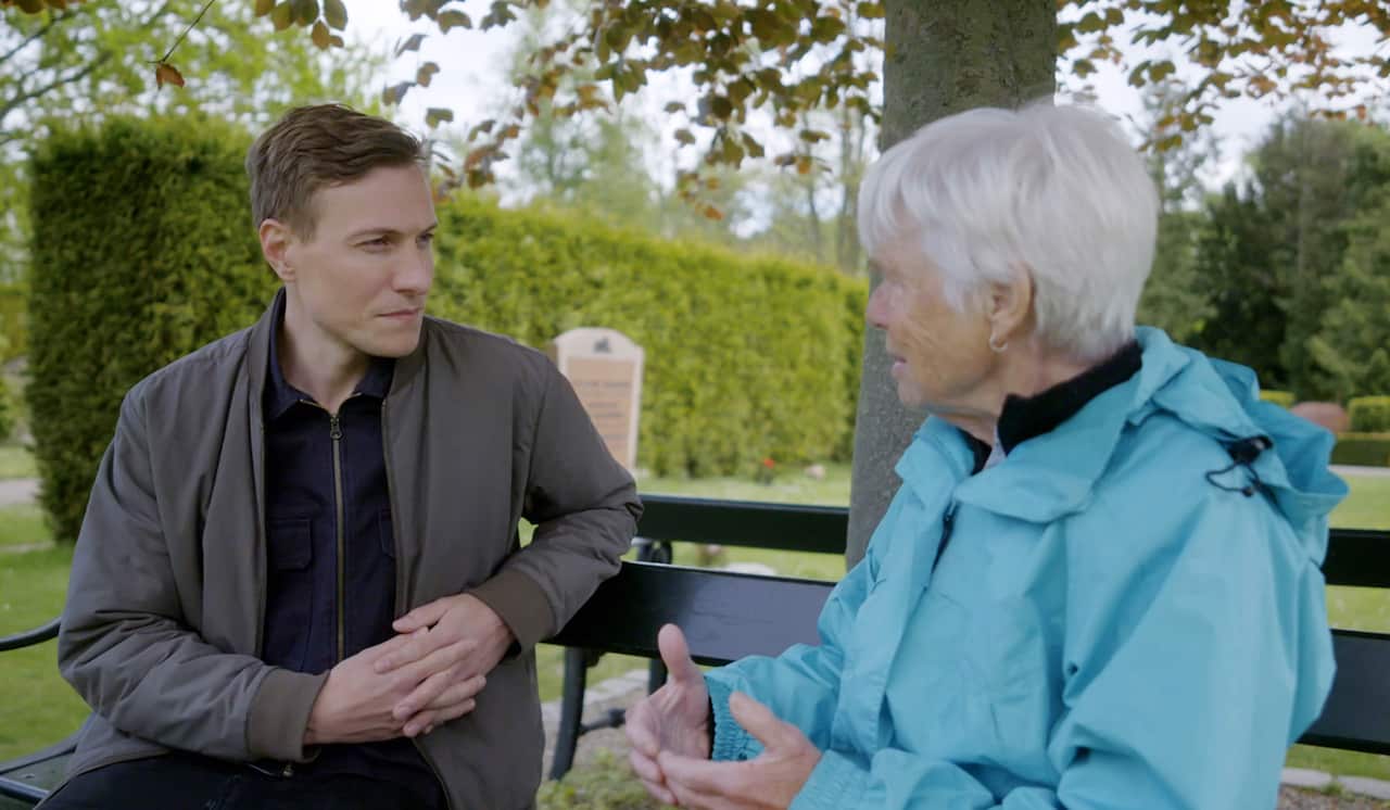 A man and a woman face each other and talk on a park bench.jpg