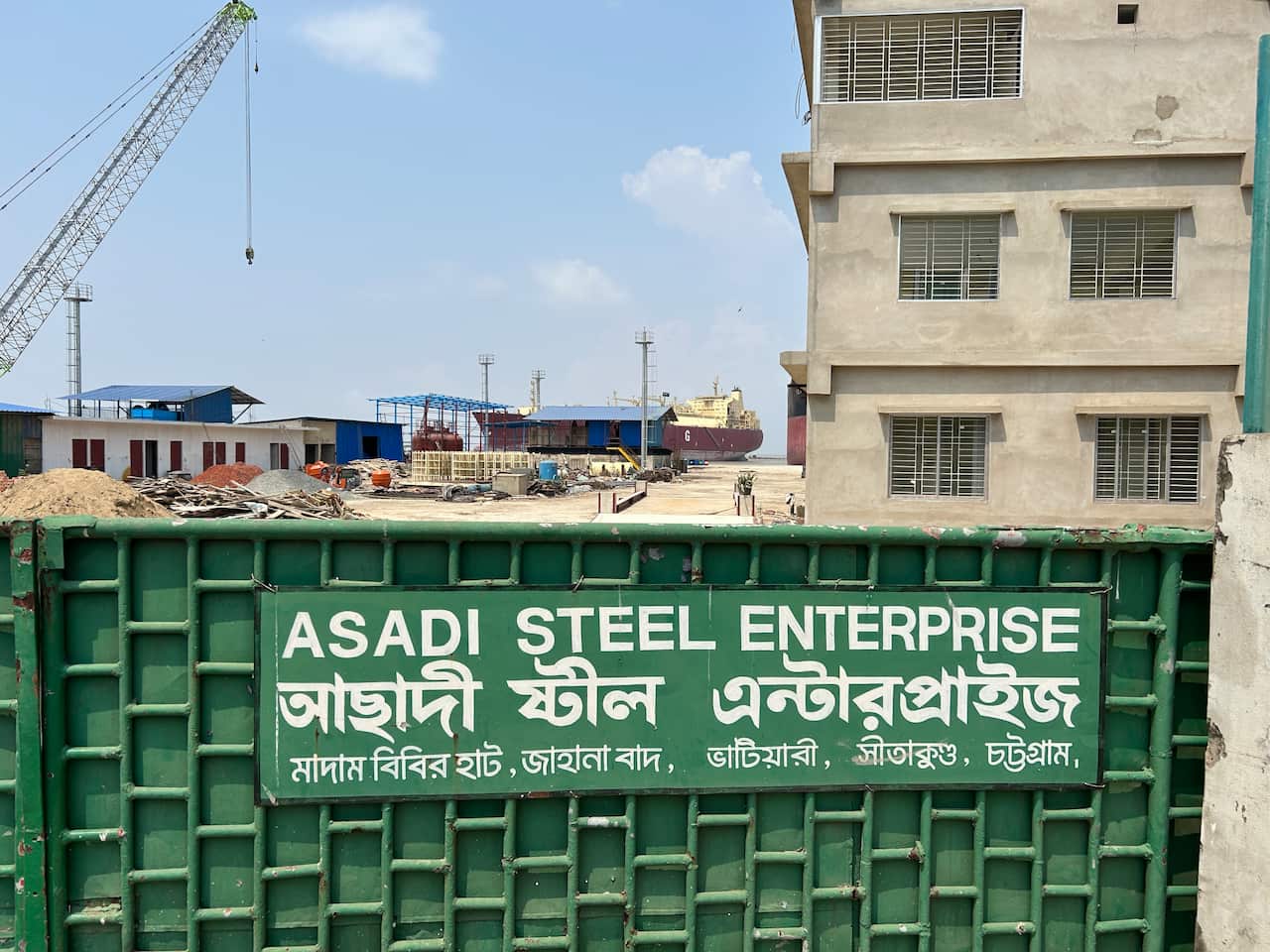 A gate to a shipbreaking yard. A sign on there reads: ASADI STEEL ENTERPRISE