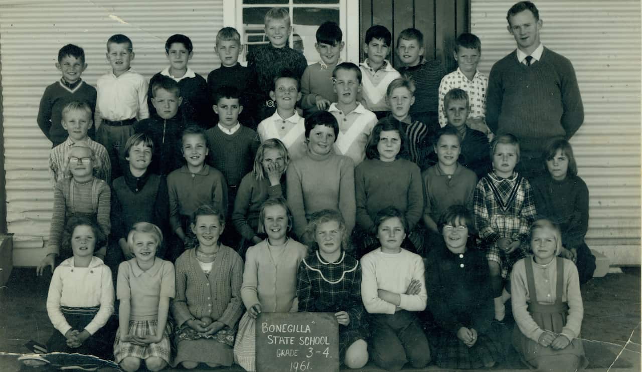 Children posing for a school photo outside. Two girls at the front hold a sign reading: Bonegilla State School. Grade 3-4 1961