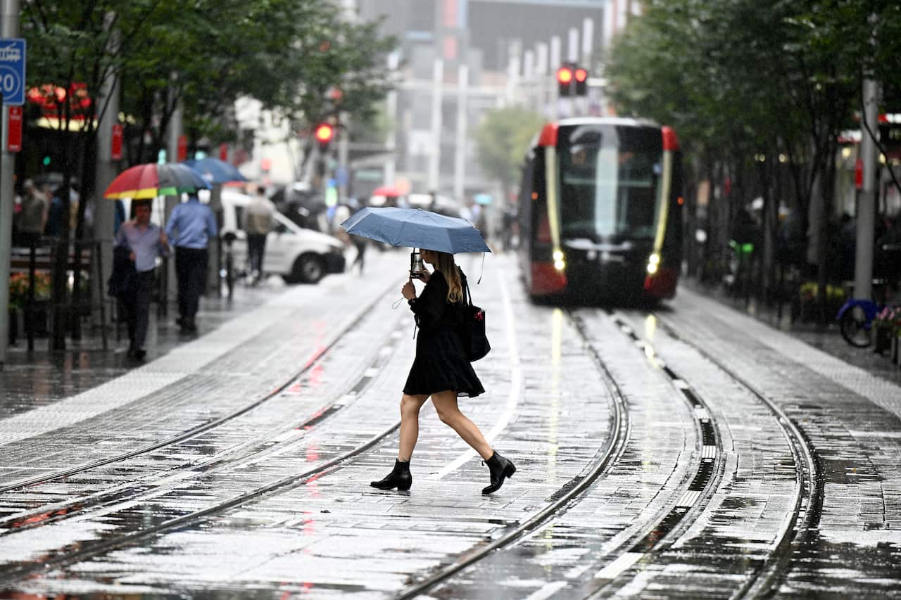 A woman crossing a road holding an umbrella