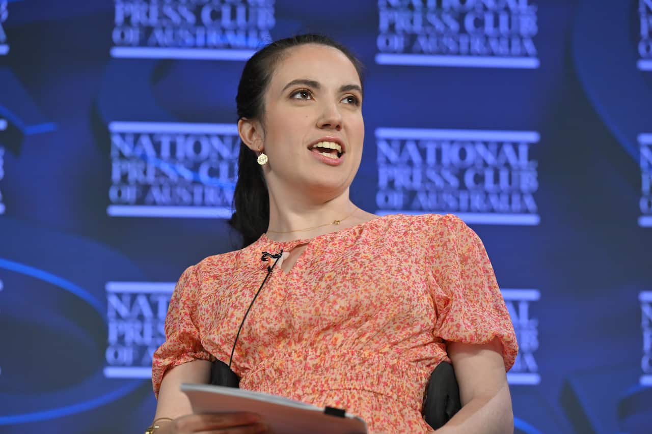 A woman in a pink floral dress in front of a purple backdrop