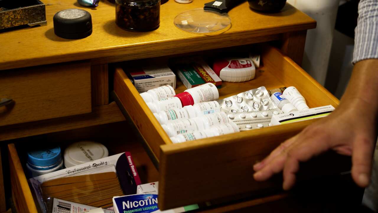 Simon opening his bedside table draw which is full of medication to treat his cluster headaches. 