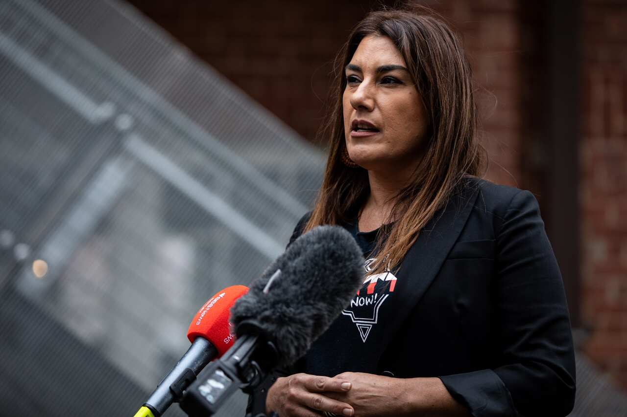 Senator Lidia Thorpe stands in front of microphones at a press conference. 