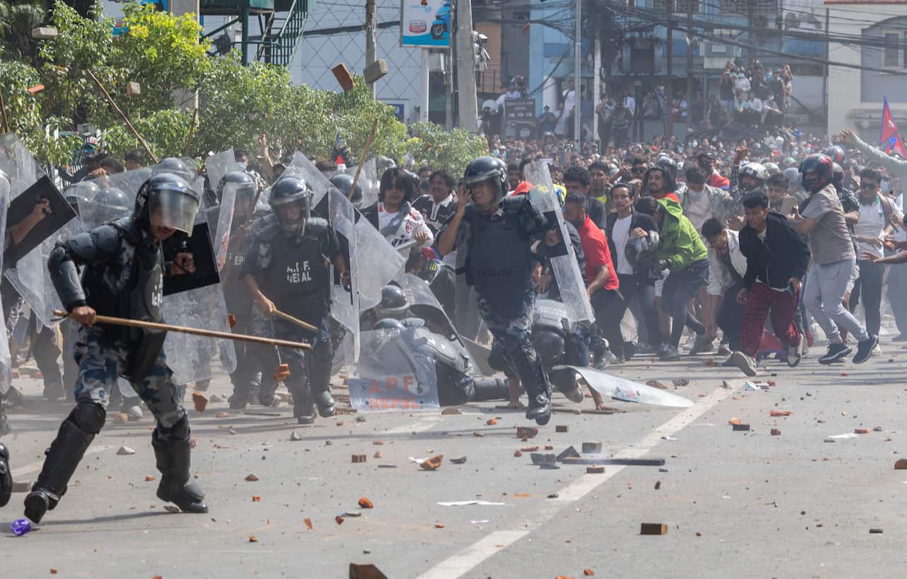 Police in riot gear clashing with protesters on a street.