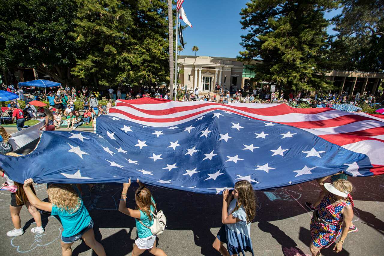 People hold giant US flag. 