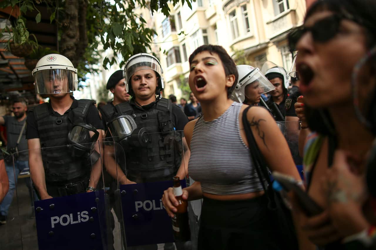 A woman chants slogans with Turkish police in the background