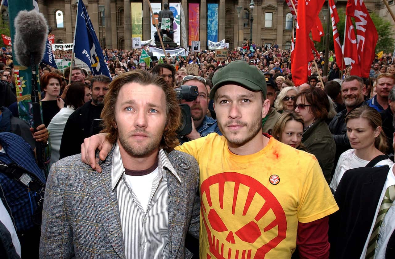 A man with his arm on another's shoulders standing in a large crowd.