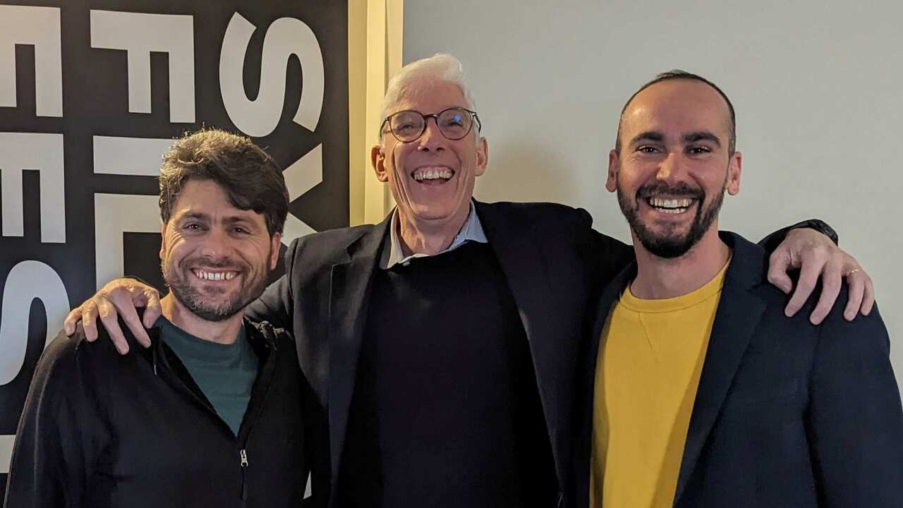 Three men, two of them young, smiling and posing for the camera.