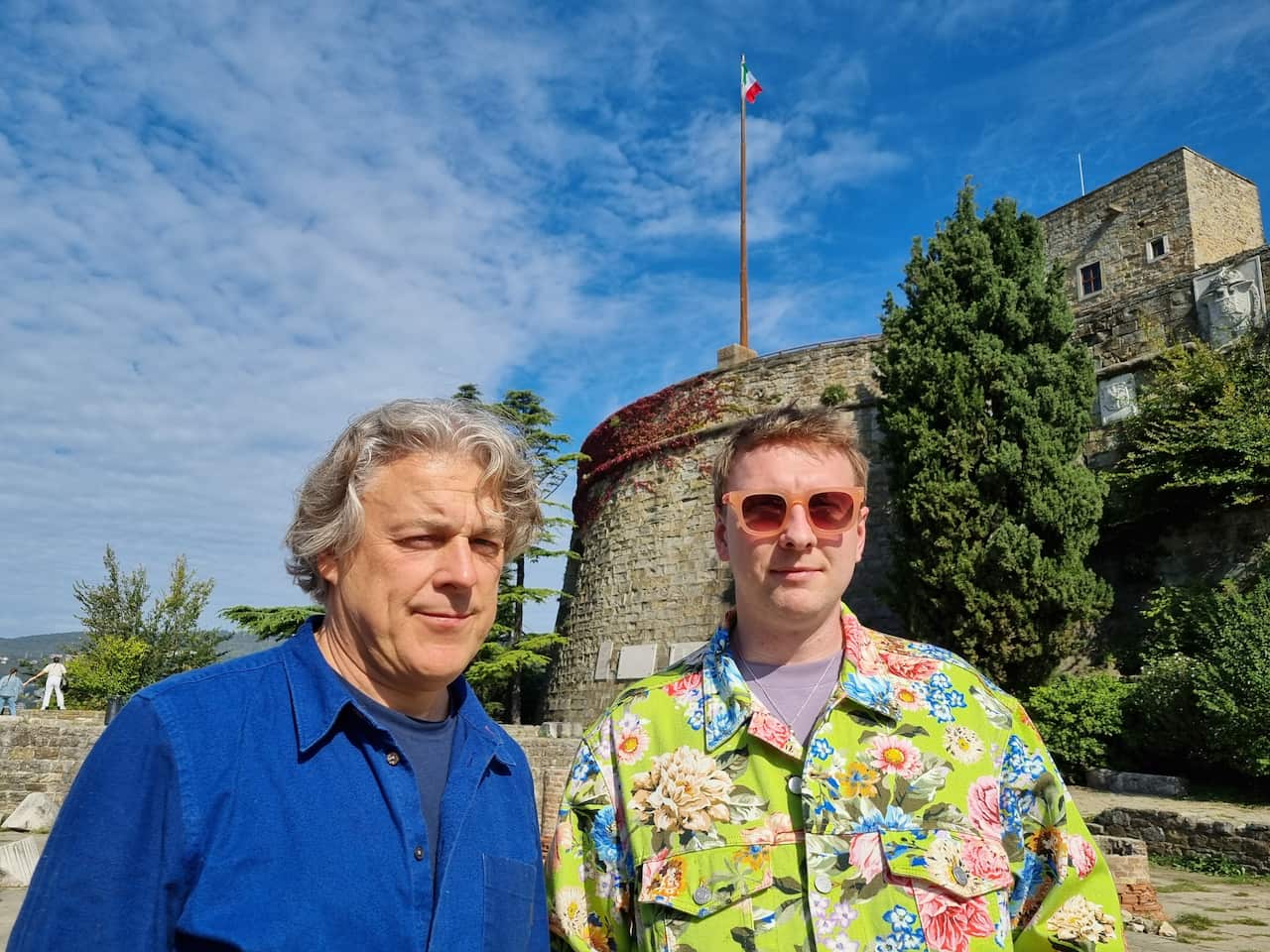 Alan Davies and Joe Lycett stand in front of a historical location in Trieste