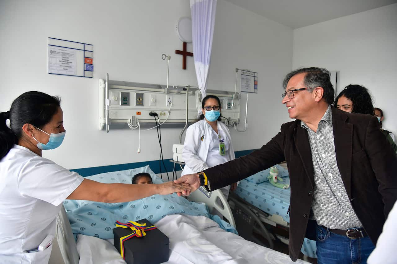 A man shaking hands with a nurse who is looking after a child at a hospital.