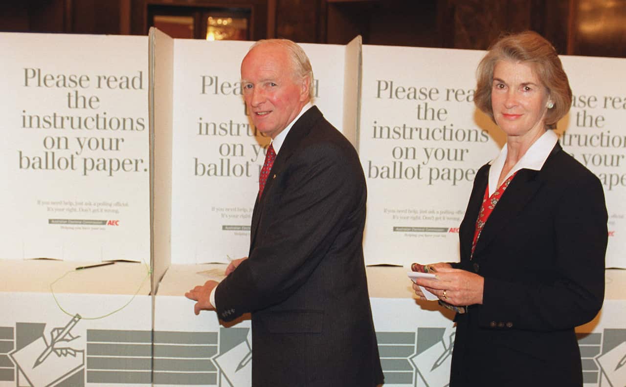 A man and a woman cast votes in a polling station. 