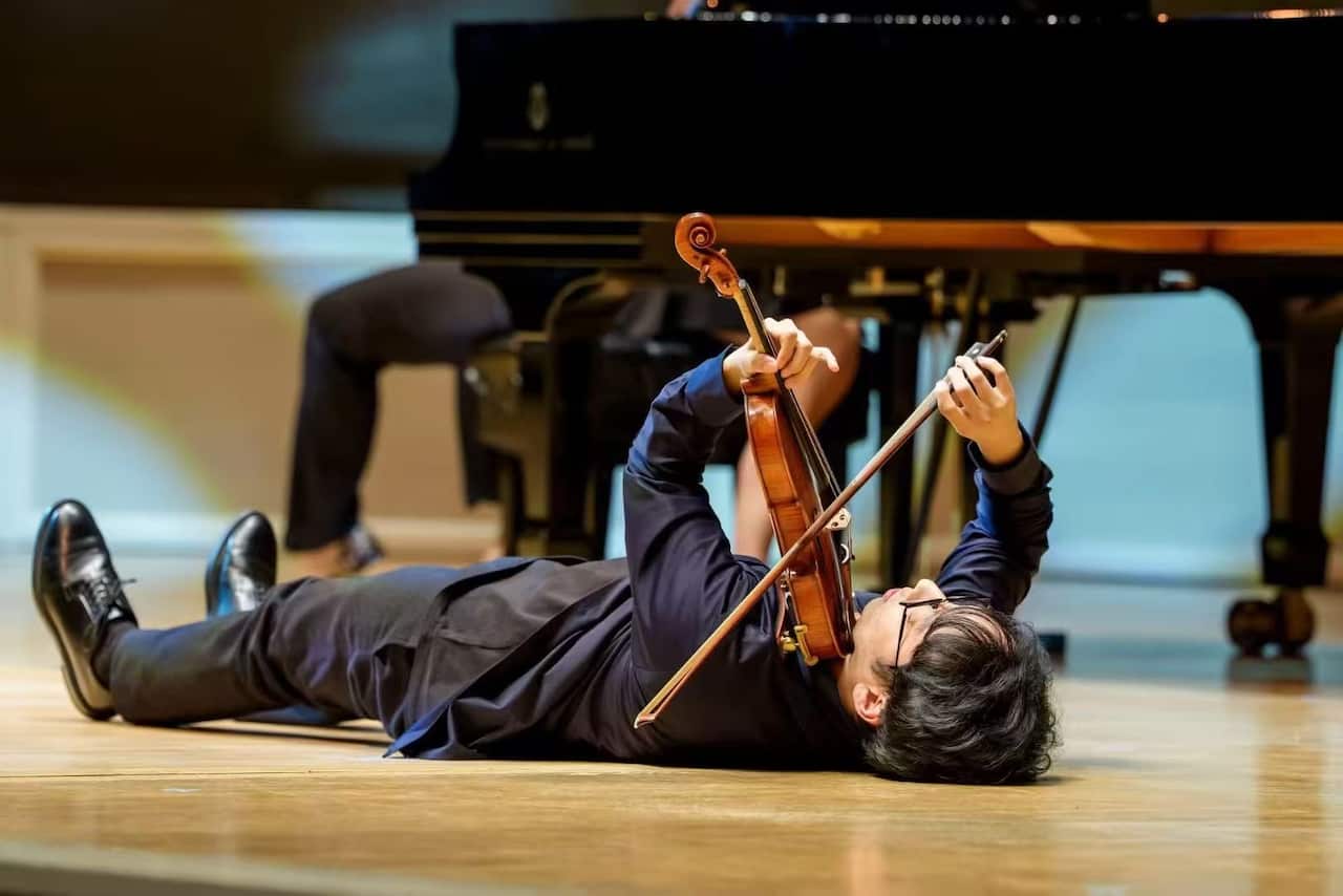 杨博尧(Brett Yang)在演出中躺在地上拉琴。