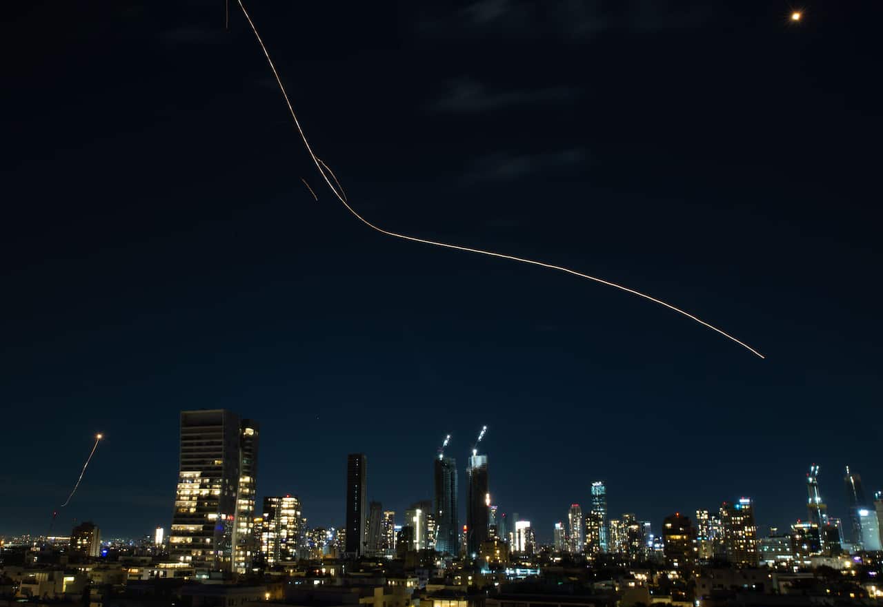A flare trail left by an interceptor missile travels across the night sky.