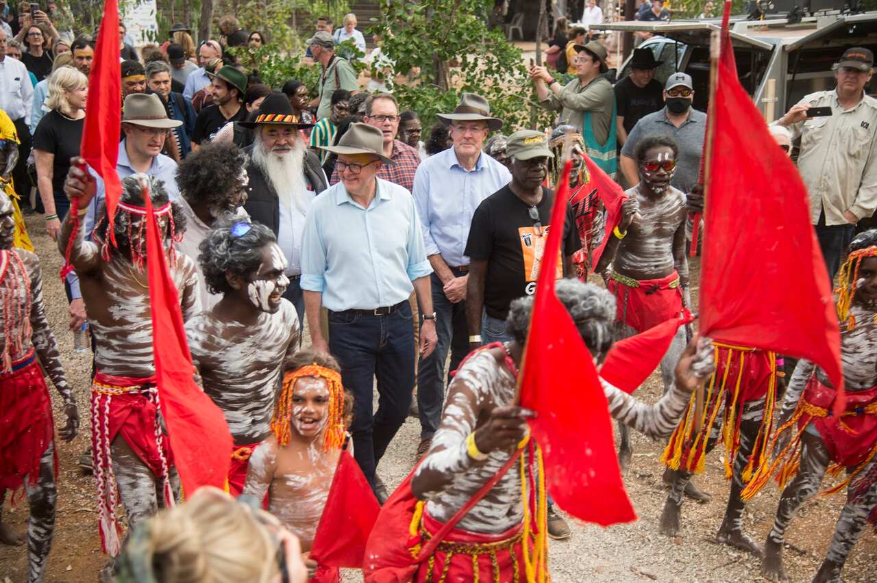 Prime Minister Anthony Albanese walking with a group of people outside 