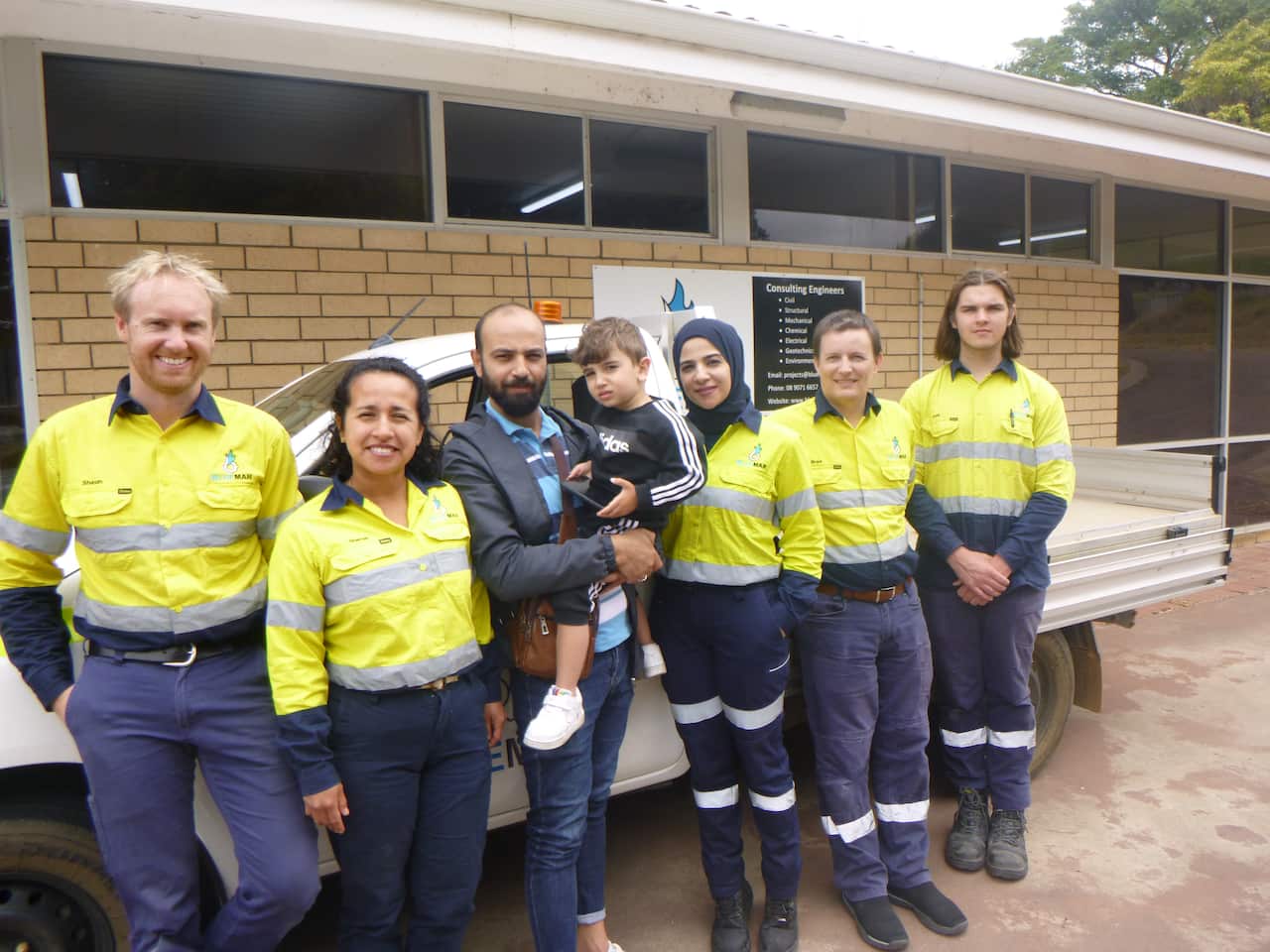 A group of people stand in front of a ute